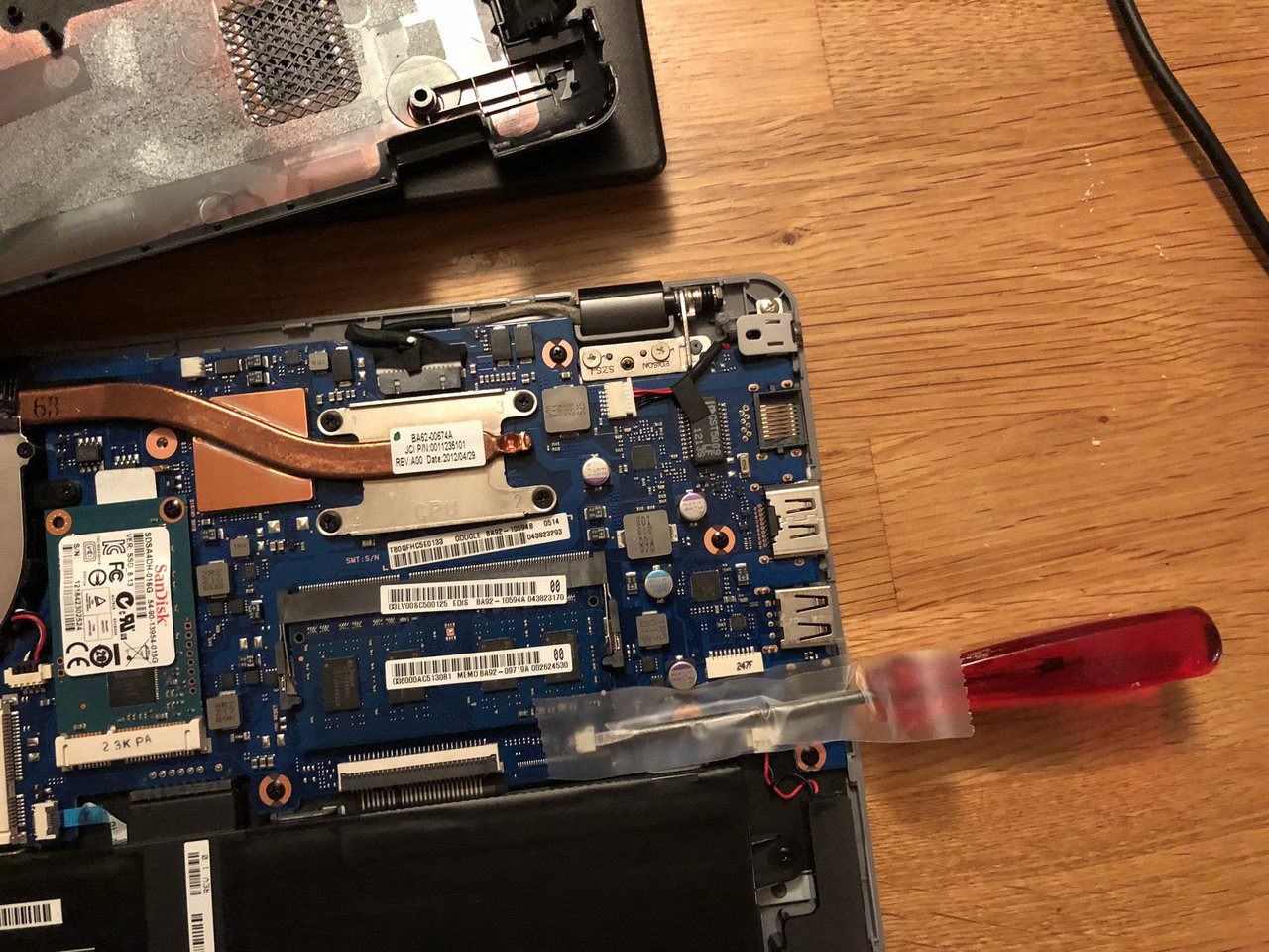 A red screwdriver shorting a jumper on the motherboard